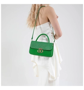 Detail of green sequin handbag featuring a gold CD twist lock on white dress background