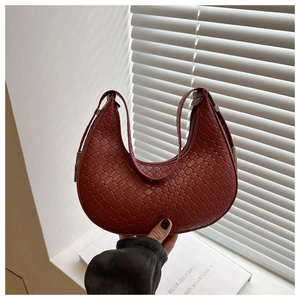 Detailed close-up of dark red woven leather texture on a crescent hobo shoulder bag