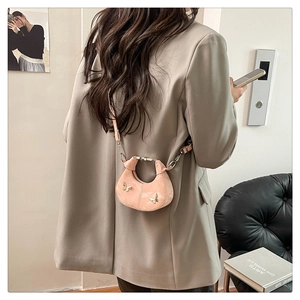 Vue détaillée d'un mini sac demi-lune rose avec décor papillon porté par un mannequin