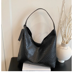 Detail of black woven Intrecciato Hobo bag with wide strap and embossed fashion tag