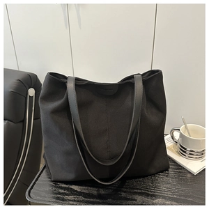 Détail du grand sac cabas noir en toile minimaliste avec longues anses et logo en cuir