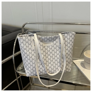 Detailed close-up of a white tote bag with M-pattern and Fashion logo on a metal rack