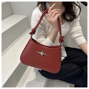 Detail of dark red woven texture shoulder bag featuring a silver star and knotted handle