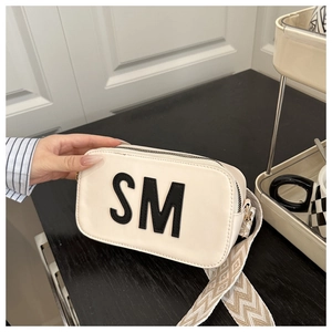 Détail du sac bandoulière beige avec lettres SM et sangle tissée géométrique