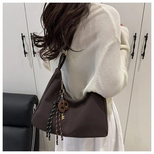 Close-up of a dark brown hobo tote bag featuring a woven knot and metal key detail