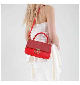 Detail of red sequin handbag with gold interlocking clasp and leather shoulder strap