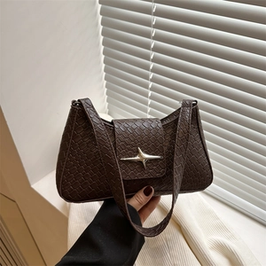 Dark brown woven leather underarm bag with silver star buckle in a sunny interior setting