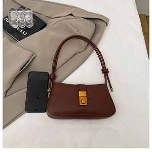 Close-up of vintage brown leather bag with golden square lock and knotted handle detail