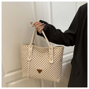 Détail du sac cabas à motif monogramme avec logo métallique et poignées en cuir beige