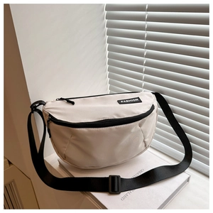 Detail of beige crescent crossbody bag with FASHION label on white book background