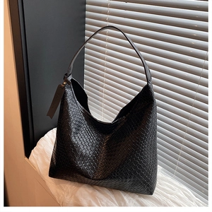 Detailed view of black woven leather tote bag texture with minimalist fashion tag