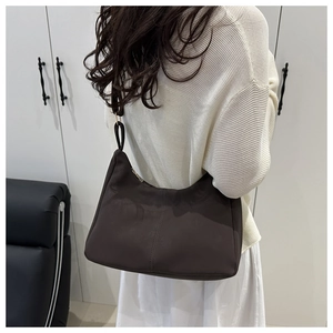 Detail of dark brown leather hobo bag featuring vertical stitching and metal zipper