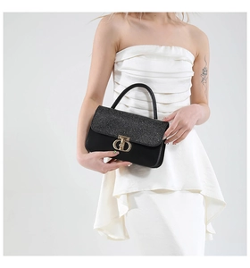 Close-up of glitter flap and golden metal clasp on black leather shoulder bag