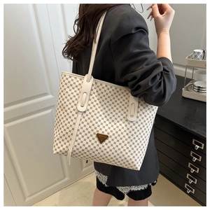 Détail du grand sac cabas avec motif à pois marron et plaque logo métallique triangulaire