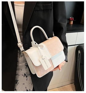 Side view of woman carrying a tricolor patchwork crossbody square bag with top handle