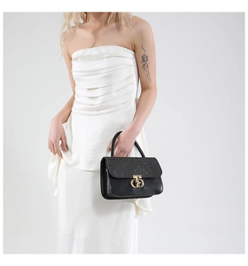 Close-up of elegant black leather handbag with sparkling glitter flap and gold CD clasp