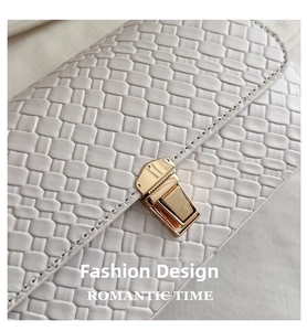 Detail of ivory woven leather bag with a rectangular gold buckle clasp and fine texture