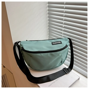Detail of mint green half-moon crossbody bag with black zipper and fashion label