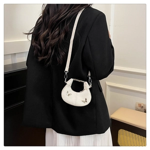 Détail d'un sac demi-lune blanc avec papillons argentés et texture en cuir élégante