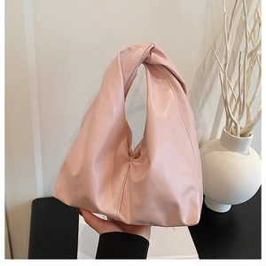 Detailed view of pink pleated bucket bag with integrated knotted handle design