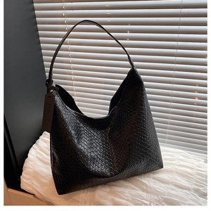 Detailed view of black woven faux leather hobo bag with a fashion tag on white fabric