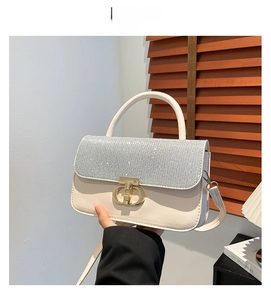 Detail of silver sequined flap on cream PU leather handbag with gold metal clasp