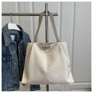 Close-up of beige tote bag with khaki handles and decorative center stitching detail