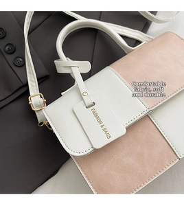 Detail of white and pink leather crossbody bag showing fashion tag on suit background