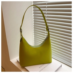 Detail of neon green hobo bag with silver zipper on white books and window shadows