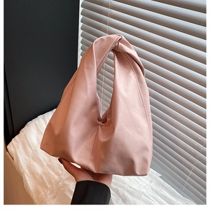 Detail of pink satin bucket bag with knotted handle and elegant pleated texture