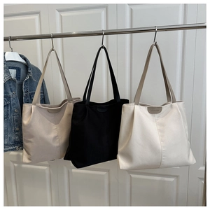 Three canvas tote bags in black, white, and beige hanging on a metal rack