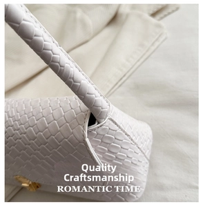 Detailed view of white woven texture leather and gold metal buckle on a shoulder bag