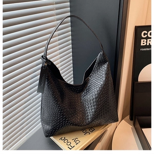 Detail of black woven texture shoulder bag with fashion tag and glossy leather finish