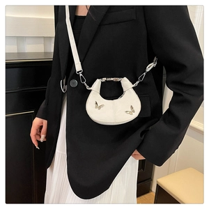 Détail du sac demi-lune blanc avec papillons argentés et poignée en métal élégante
