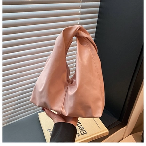 Close-up of pink pleated bucket bag with twisted handle and soft matte leather texture