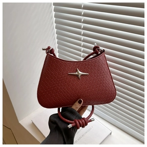 Detailtextur der dunkelroten geflochtenen Handtasche mit silbernem Stern-Metallornament