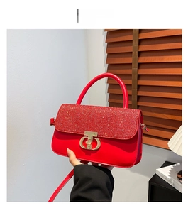 Detail of red crossbody bag featuring luxury crystal-embellished flap and metal buckle