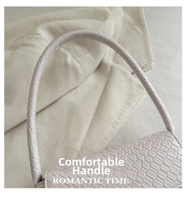 Detail of cream woven shoulder bag featuring intricate texture and comfortable handle