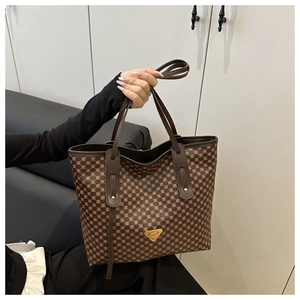 Détail d'un sac cabas marron à motif géométrique avec anses en cuir et logo doré