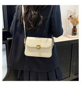 Détail d'un sac bandoulière crème avec fermoir métallique doré vintage sur similicuir lisse