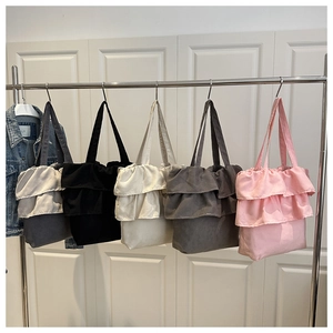 Detailed row of pleated canvas tote bags in five different colors on a metal rack