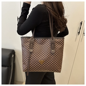 Vue détaillée de la plaque métallique dorée sur le sac cabas au motif géométrique rétro