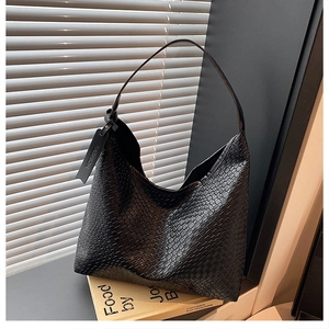 Close-up of black woven leather shoulder bag showing intricate texture and fashion tag