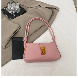 Detailed shot of pink underarm bag with gold metal clasp and thin knotted straps
