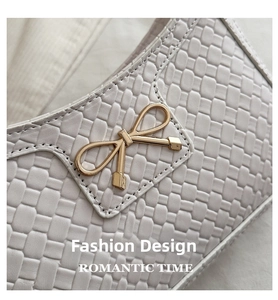 Close-up of white woven shoulder bag texture with golden bow buckle detail