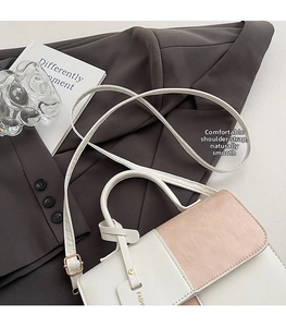Detail of trendy pink and white patchwork crossbody bag with decorative letter tag