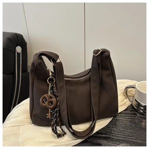 Detail of dark brown tote bag featuring unique pretzel and key charms on soft fabric
