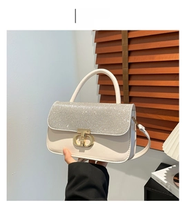 Detail of elegant beige handbag featuring a crystal-encrusted flap and gold interlocking clasp