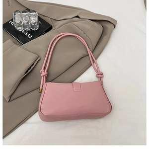 Close-up of pink shoulder bag featuring unique knotted strap detail and sleek matte PU finish