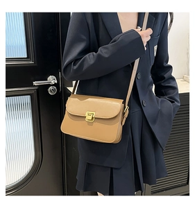 Gros plan d'un sac bandoulière camel avec une boucle en métal doré rectangulaire classique